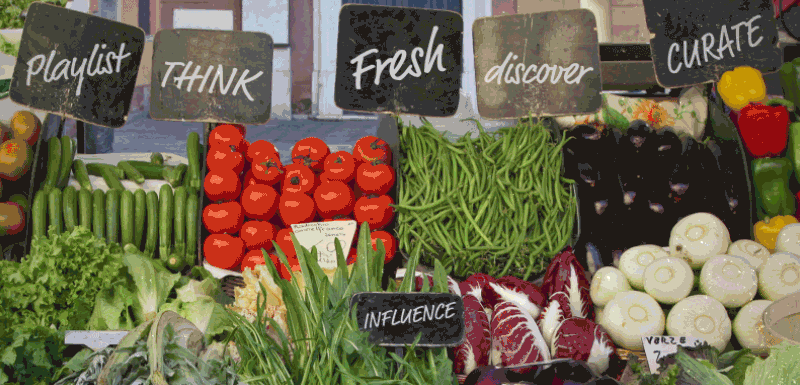 A beautiful image of fresh ingredients, carefully displayed in a greengrocer window. Produce labels are playlist, think, fresh, curate, discover, influence.